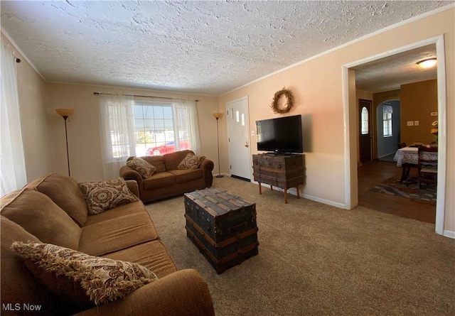 living area featuring arched walkways, a textured ceiling, carpet flooring, baseboards, and ornamental molding