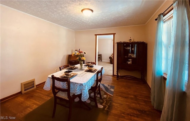 dining room with crown molding, dark wood finished floors, visible vents, a textured ceiling, and baseboards