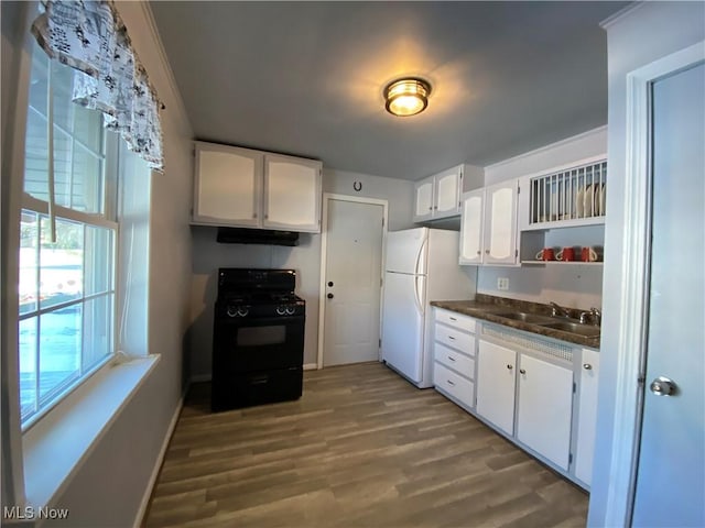 kitchen with black gas range, a sink, white cabinetry, freestanding refrigerator, and dark countertops