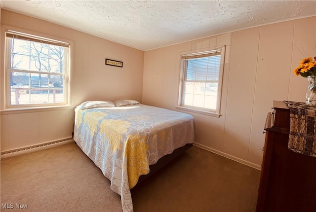 carpeted bedroom with a textured ceiling, multiple windows, baseboard heating, and a decorative wall