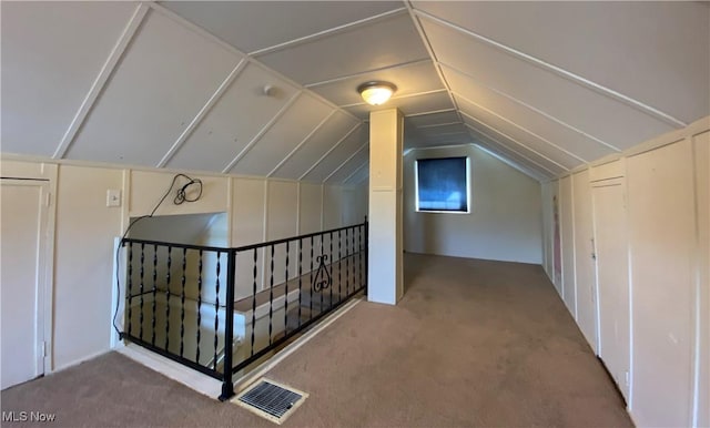 additional living space featuring carpet floors, visible vents, and vaulted ceiling