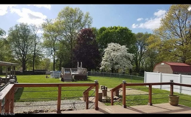 deck featuring a pool, a fenced backyard, and a lawn