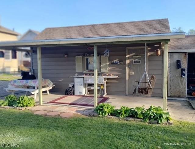 rear view of house with a yard and a shingled roof