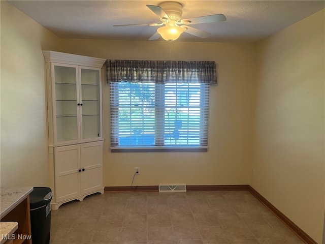 unfurnished dining area with baseboards, visible vents, and ceiling fan