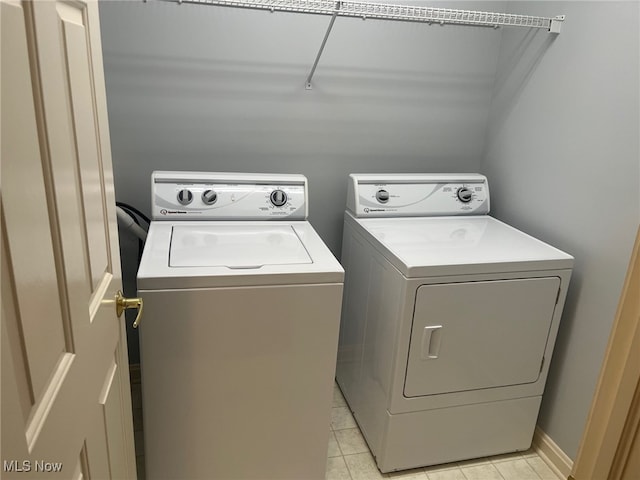 clothes washing area featuring laundry area, light tile patterned floors, baseboards, and separate washer and dryer