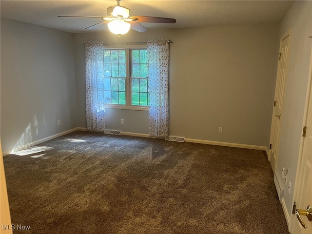 empty room with dark carpet, visible vents, and baseboards