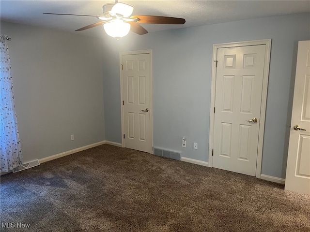 carpeted spare room with baseboards, visible vents, and ceiling fan