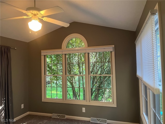 carpeted spare room featuring lofted ceiling, visible vents, and a healthy amount of sunlight