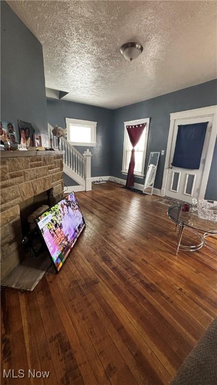 interior space featuring a textured ceiling, wood finished floors, stairs, and baseboards