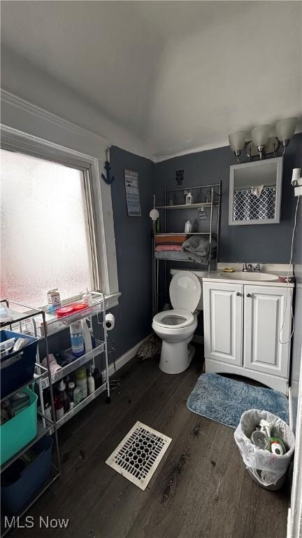 half bathroom with baseboards, toilet, wood finished floors, vaulted ceiling, and vanity