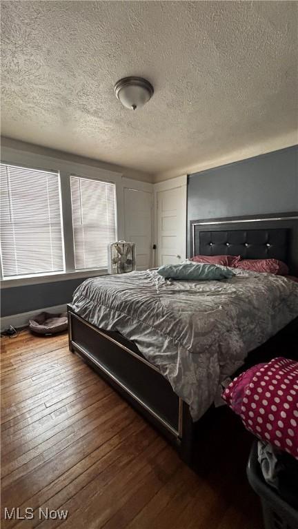 bedroom with a textured ceiling and wood finished floors