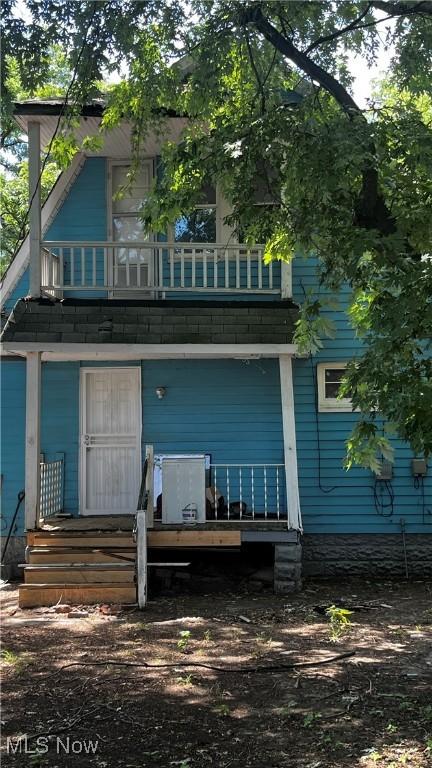 rear view of property featuring a balcony and covered porch