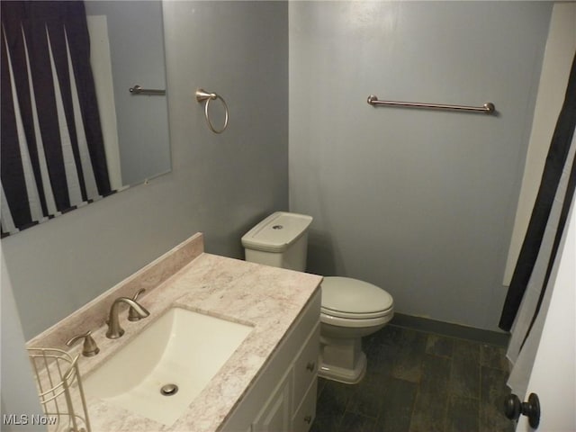 bathroom featuring wood finished floors, vanity, toilet, and baseboards