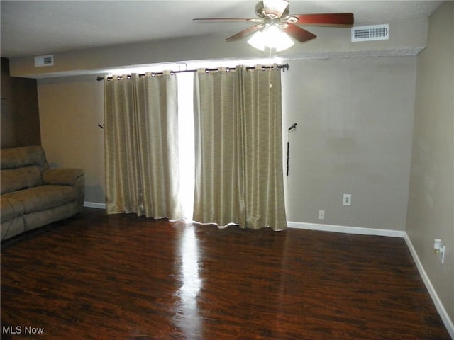 unfurnished living room with dark wood-style floors, a ceiling fan, visible vents, and baseboards