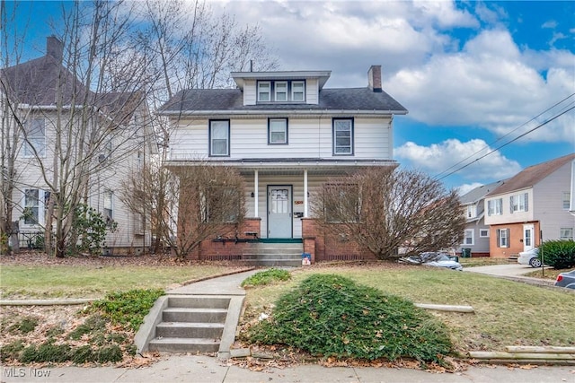 traditional style home featuring brick siding, a chimney, and a front yard