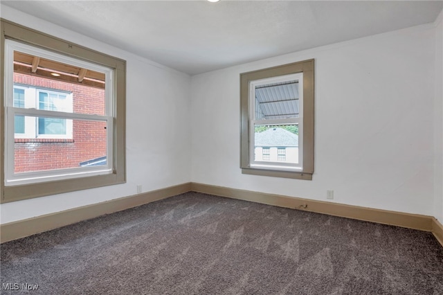 spare room with dark colored carpet and baseboards