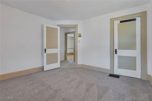 empty room with ornamental molding, visible vents, light carpet, and baseboards