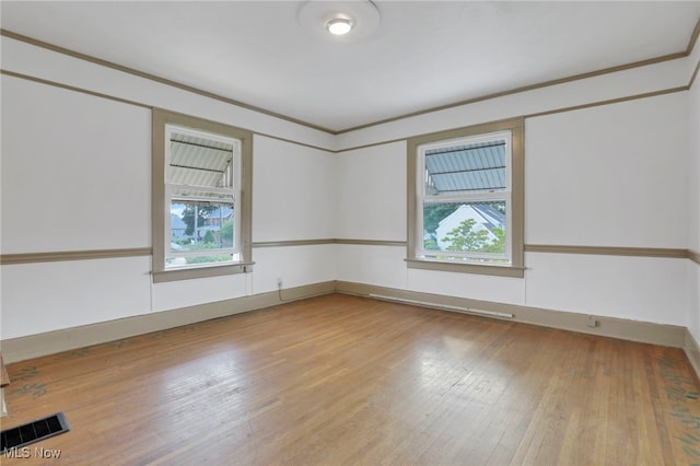 spare room with light wood-style flooring, visible vents, and crown molding