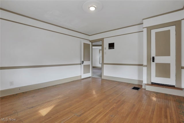 empty room with baseboards, ornamental molding, and wood finished floors