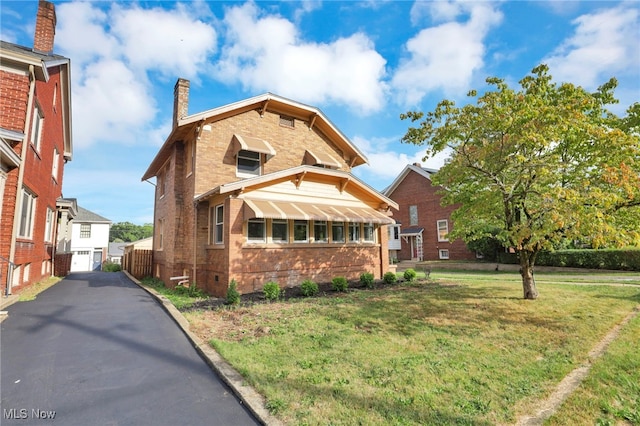 view of front facade with brick siding, fence, a chimney, and a front lawn