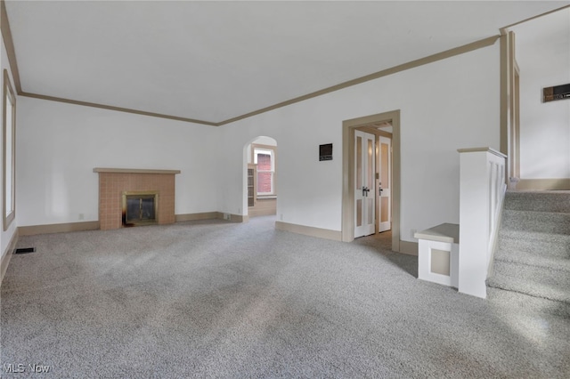 unfurnished living room with arched walkways, carpet flooring, a fireplace, and stairs