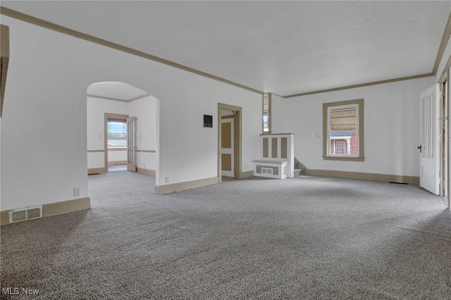 unfurnished living room featuring arched walkways, carpet flooring, visible vents, baseboards, and ornamental molding