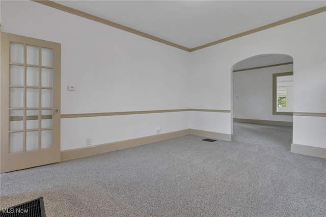 unfurnished room with visible vents, arched walkways, baseboards, ornamental molding, and carpet floors