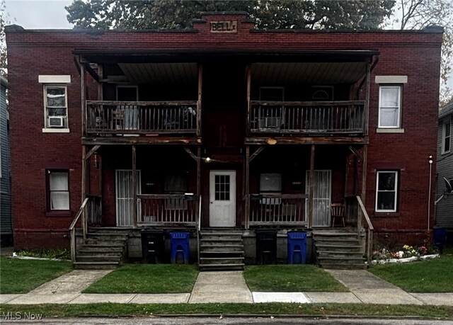 townhome / multi-family property with a porch, brick siding, and a balcony