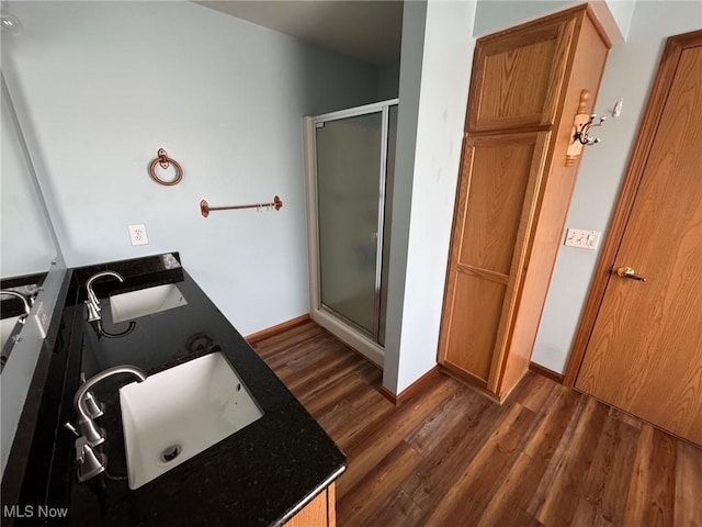 bathroom with a sink, a shower stall, and wood finished floors