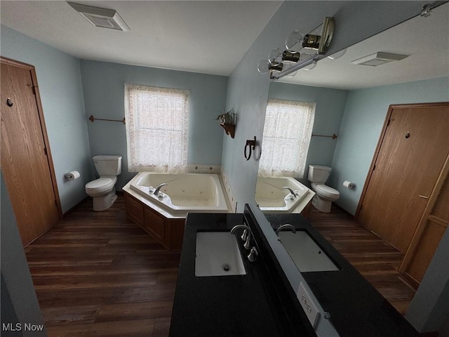 bathroom featuring a whirlpool tub, visible vents, toilet, and wood finished floors