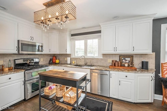 kitchen with appliances with stainless steel finishes, dark wood-type flooring, a sink, and white cabinets