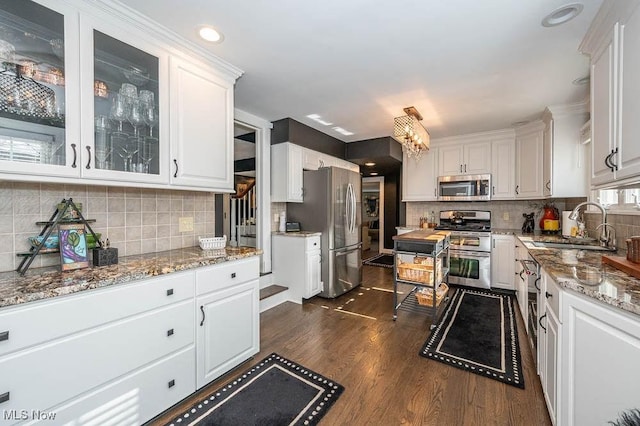 kitchen featuring glass insert cabinets, white cabinetry, stainless steel appliances, and a sink