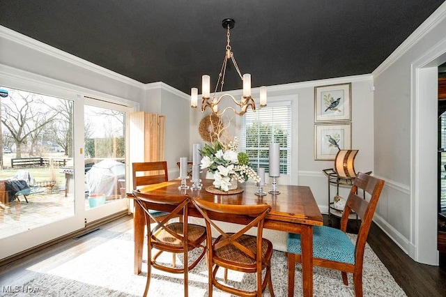 dining area with an inviting chandelier, wood finished floors, visible vents, and crown molding