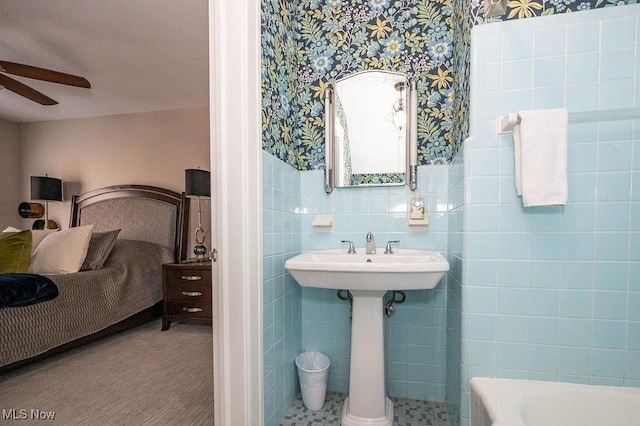 full bathroom featuring a bathtub, a wainscoted wall, tile walls, ceiling fan, and wallpapered walls