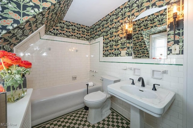 bathroom featuring toilet, wallpapered walls, a bathtub, and tile walls