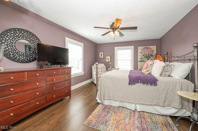 bedroom featuring ceiling fan, multiple windows, baseboards, and dark wood-style flooring