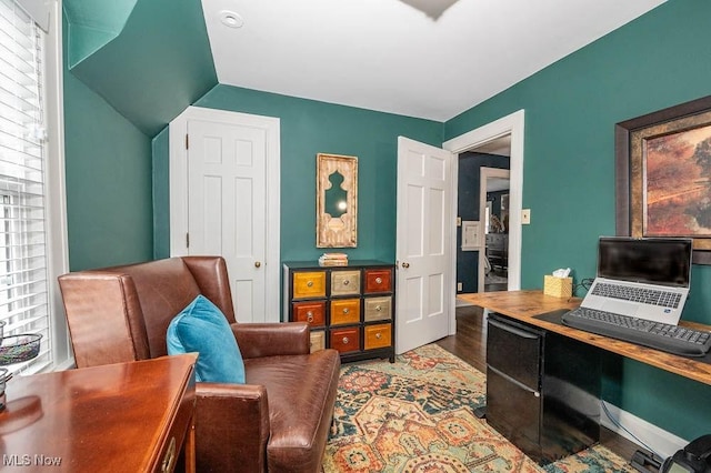 office space with lofted ceiling, wood finished floors, and baseboards