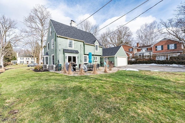 back of house featuring a garage, a lawn, a chimney, an outdoor structure, and central air condition unit