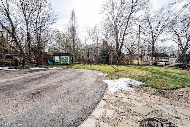 view of yard featuring an outbuilding, a storage unit, and fence