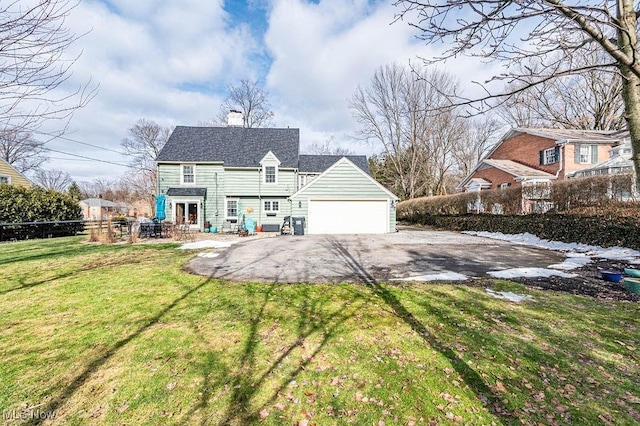 back of property with a garage, a lawn, a chimney, aphalt driveway, and fence