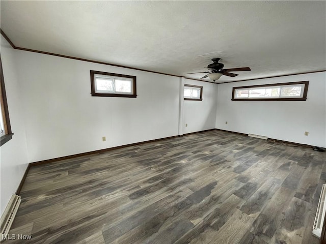 empty room with baseboards, ceiling fan, dark wood-style flooring, crown molding, and a baseboard heating unit