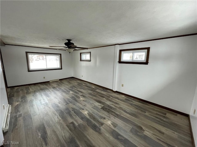 unfurnished room with a textured ceiling, a baseboard radiator, dark wood-type flooring, baseboards, and ornamental molding