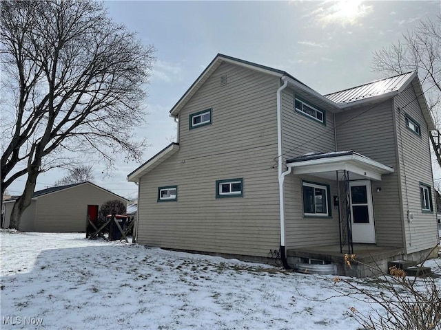 snow covered house featuring metal roof