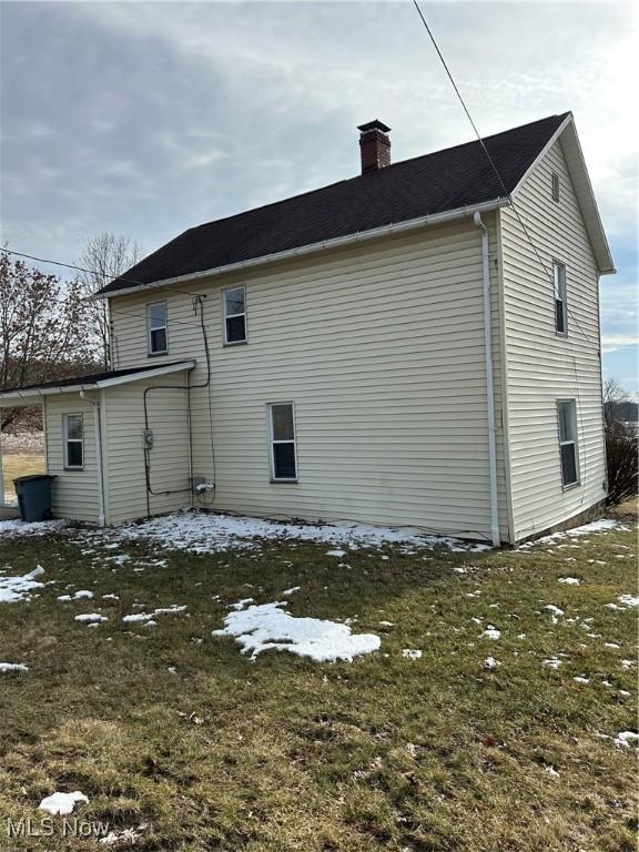 snow covered property featuring a lawn and a chimney