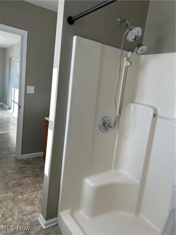 full bath with a shower stall and baseboards