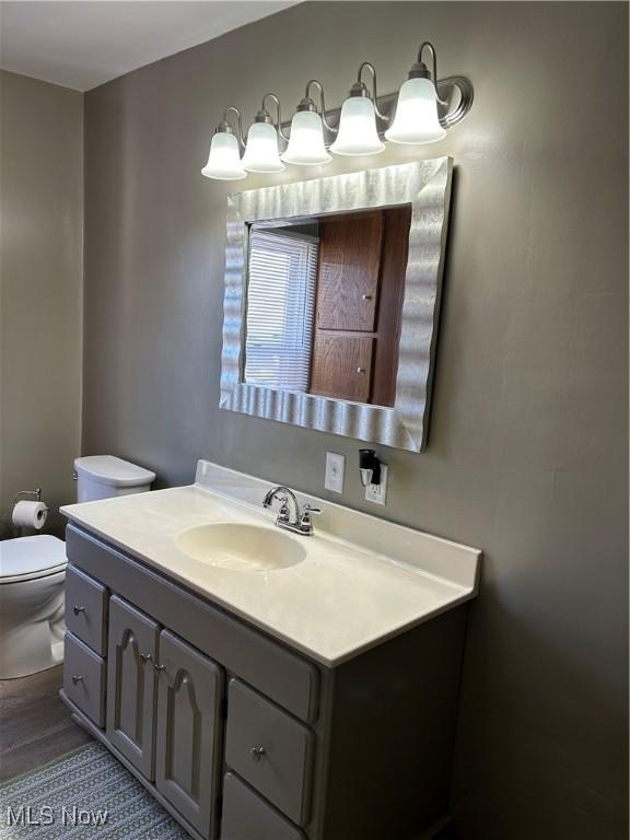 bathroom with toilet, wood finished floors, and vanity