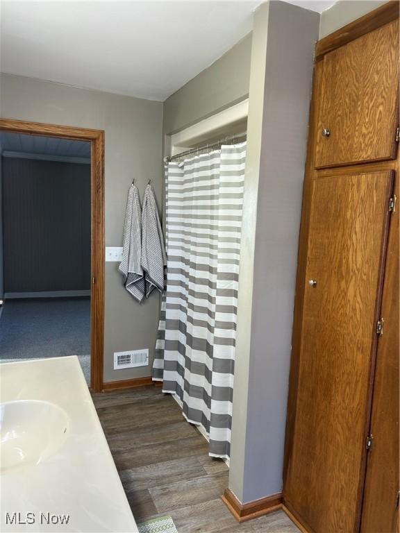 bathroom with wood finished floors, a sink, visible vents, and baseboards