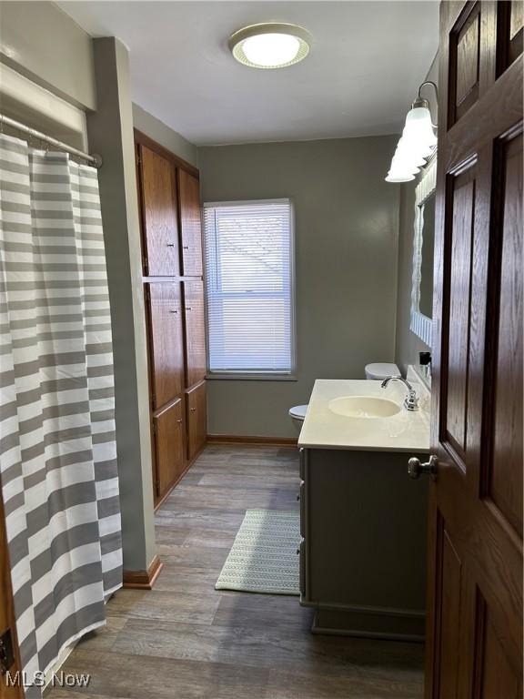 full bath featuring toilet, wood finished floors, vanity, and baseboards