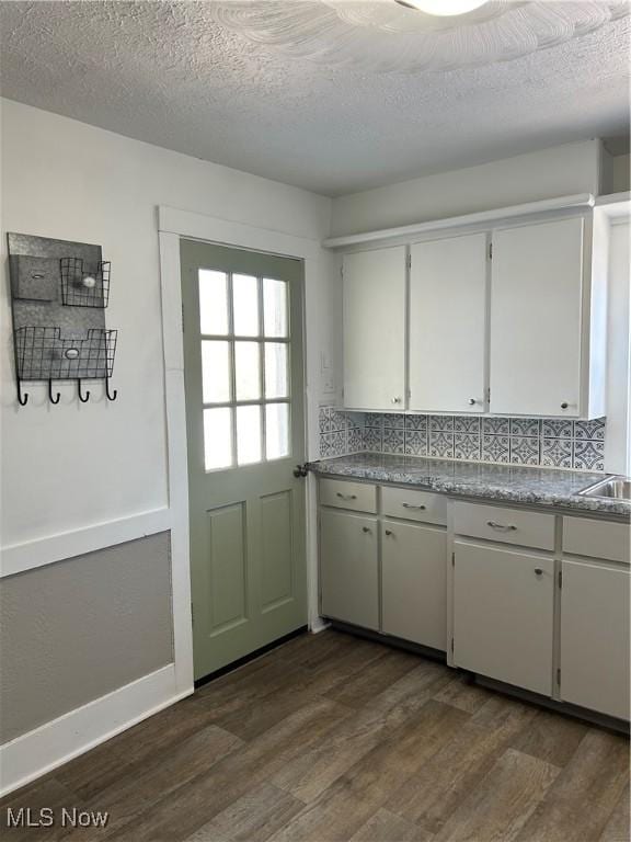 kitchen featuring tasteful backsplash, dark wood-style flooring, white cabinetry, and a textured ceiling