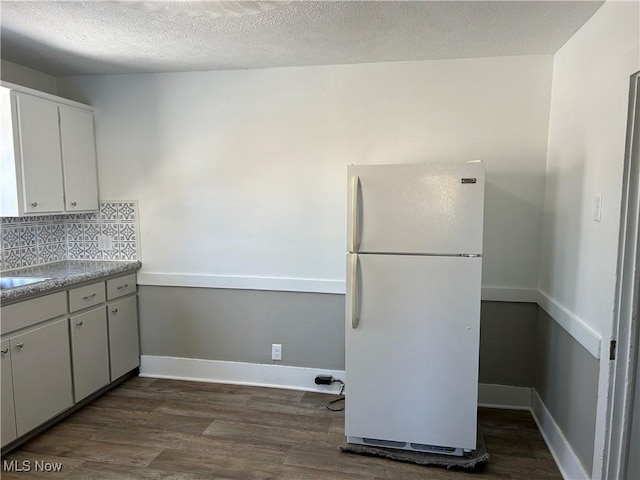 kitchen featuring tasteful backsplash, dark wood finished floors, white cabinets, freestanding refrigerator, and light countertops